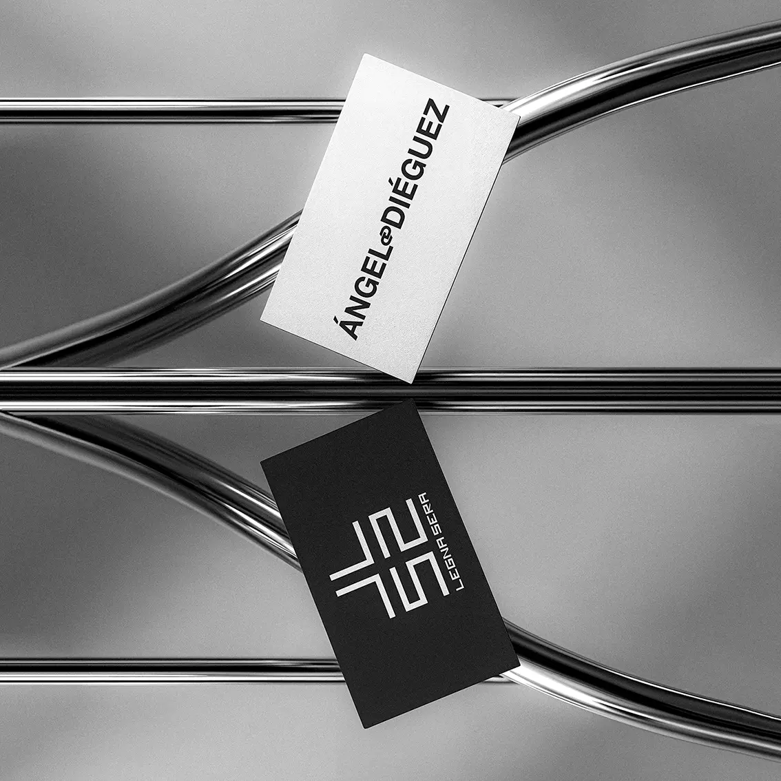 Ángel Diéguez business cards resting on chrome tubes, one white with the name and one black with the Legna Sera monogram, branding and identity design