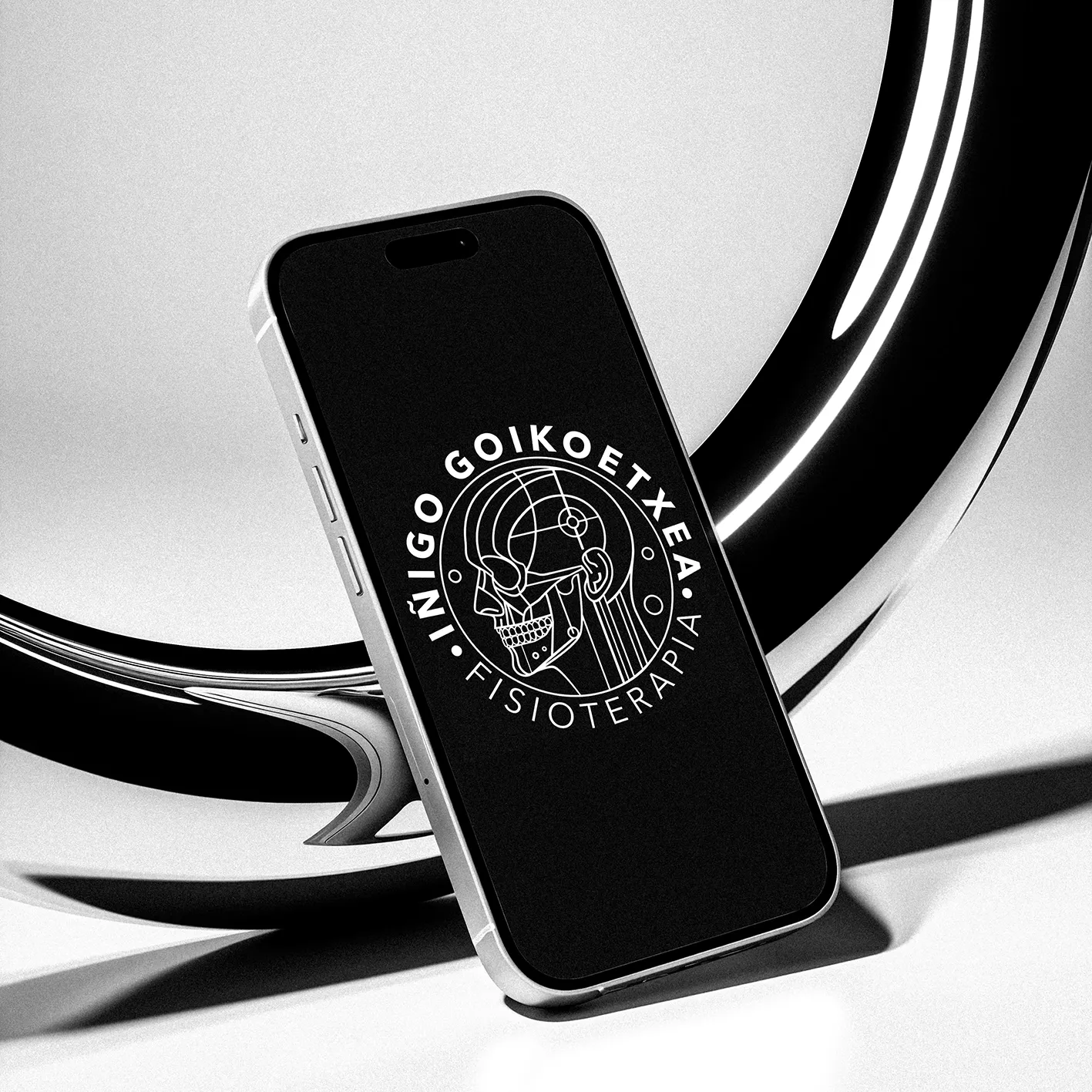 Iñigo Goikoetxea Fisioterapia logo on a phone screen: a white line-art anatomical skull with circular lettering on a black background.