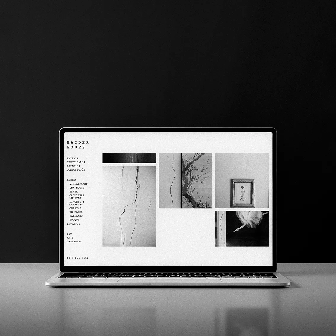 Maider Egues photography website on a laptop, showing a series menu and a black-and-white gallery on a minimalist dark background.