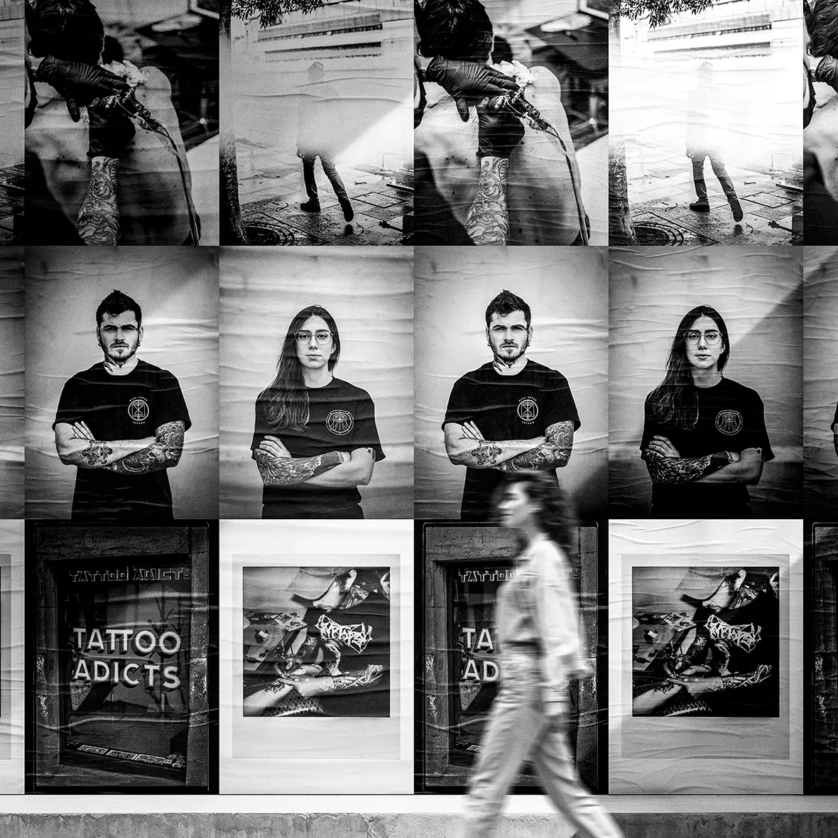 Wall plastered with black and white Tattoo Adicts campaign posters of artists, storefront and details, with a woman walking past
