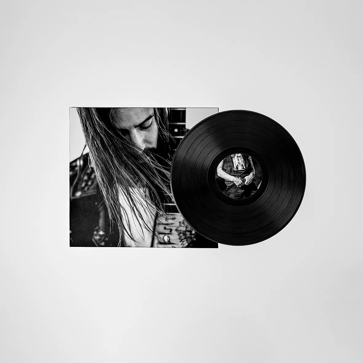 We Are Nómadas vinyl album with a black-and-white cover of a long-haired musician and a black record on a light grey backdrop.